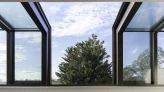 Ventana amplia con marcos oscuros, mostrando un paisaje exterior con un árbol y cielo parcialmente nublado. Interior moderno con pared blanca y suelos de madera clara.