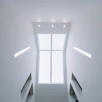 Techo interior con una ventana grande que deja pasar luz natural. Paredes blancas y luces empotradas. Escalera visible en la parte inferior.