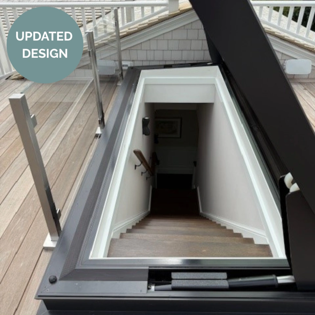 Un descensore con una scala che conduce a un piano inferiore, circondata da un bordo moderno e finestre di vetro. Un segno verde indica "Design Aggiornato".
