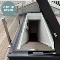 Un descensore con una scala che conduce a un piano inferiore, circondata da un bordo moderno e finestre di vetro. Un segno verde indica "Design Aggiornato".